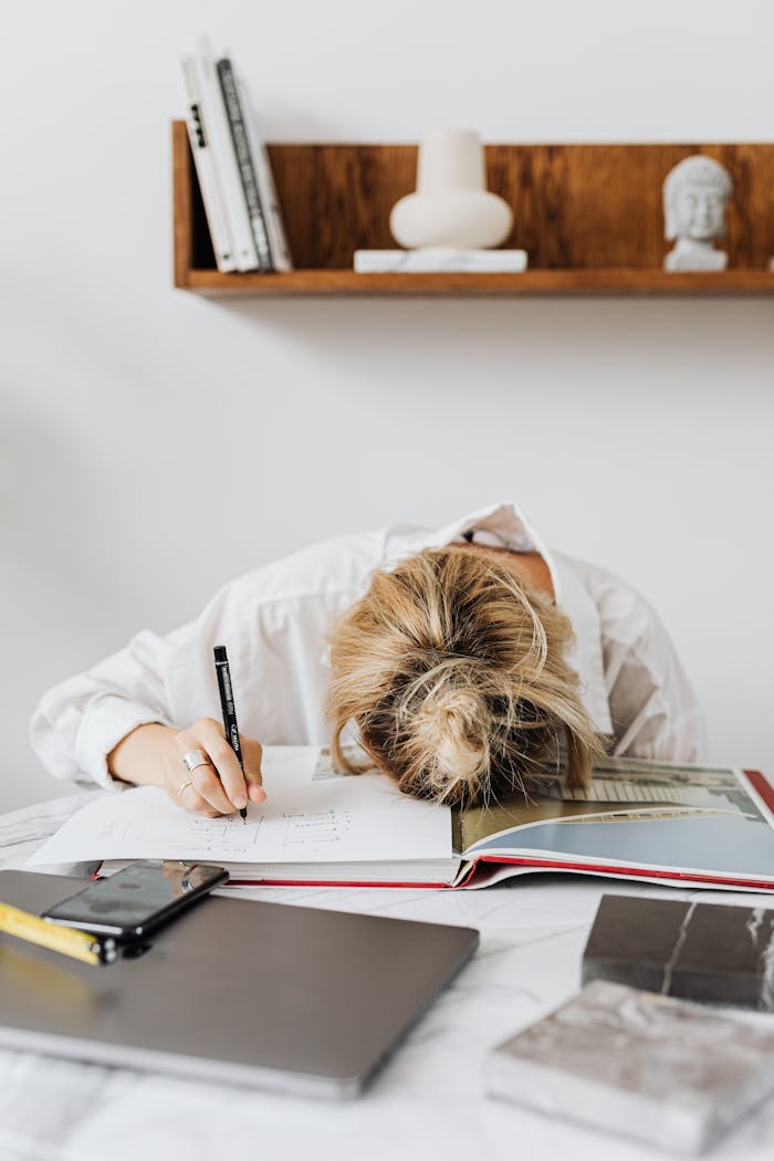 Frustrated woman overwhelmed with work, head down on desk in home office.